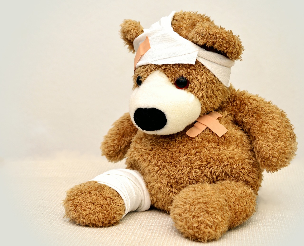 teddybjørn med plaster på magen og bandasje på hode og ben