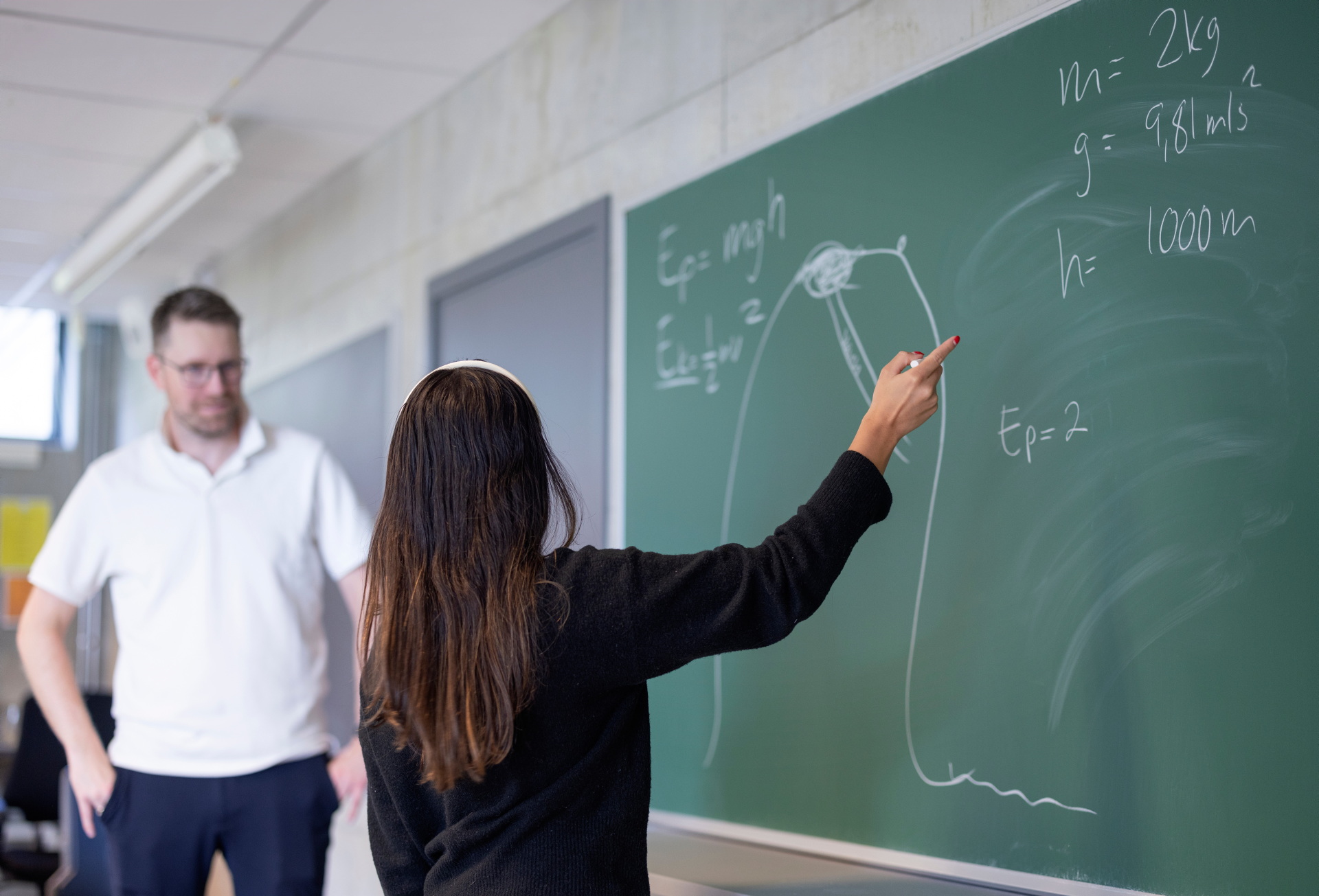 Mannlig lærer underviser kvinnelig student ved tavlen