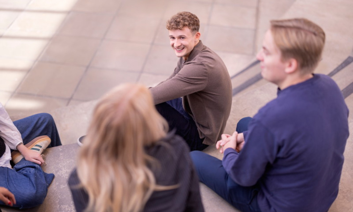 Fire studenter sitter i en gruppe og prater.