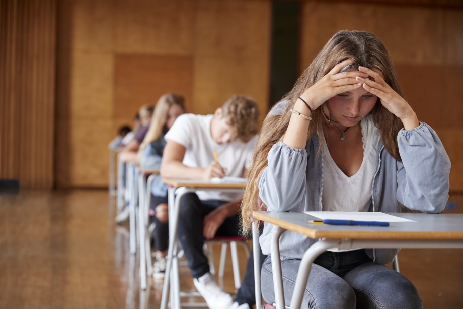 Elev sitter ved pult med hodet i hendene