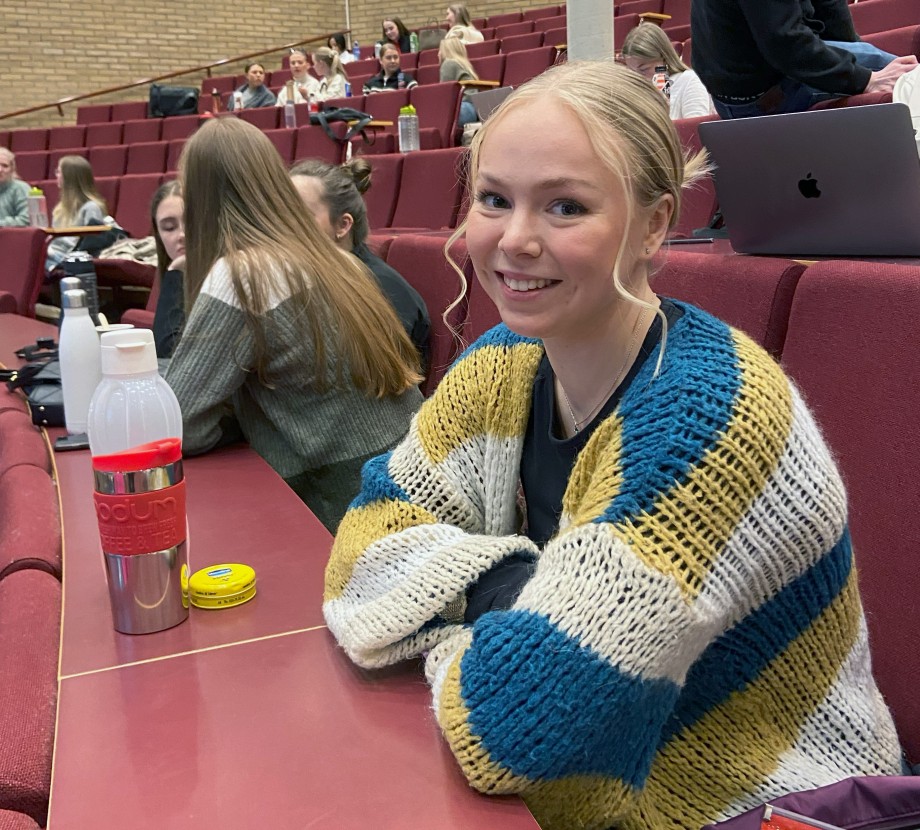 Smilende kvinnelig student i auditorium.