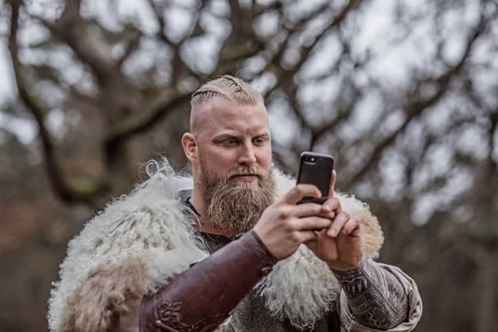 A modern 'Viking' warrior in the forest using a smartphone